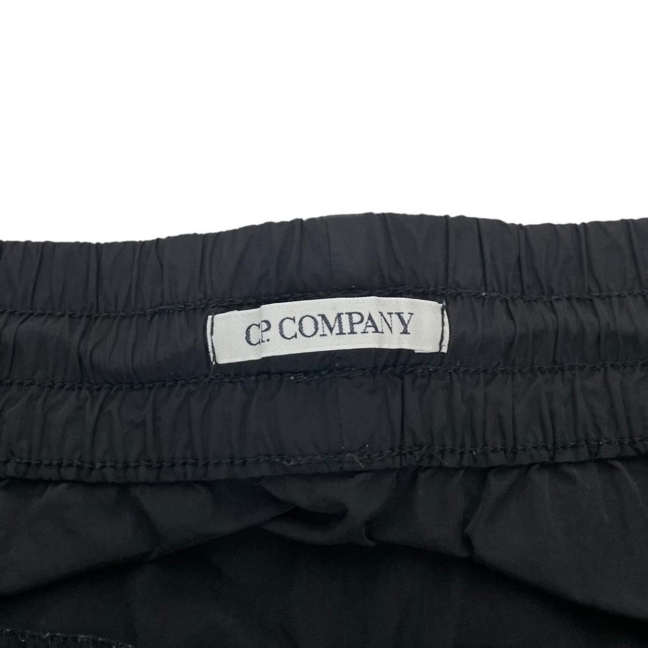 CP Company black cargo trousers with lens detail and nylon material.