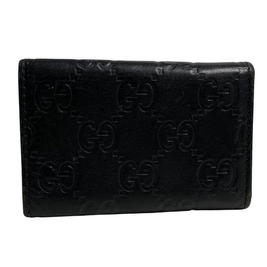 Gucci black leather key case featuring GG monogram pattern and scuffed details.