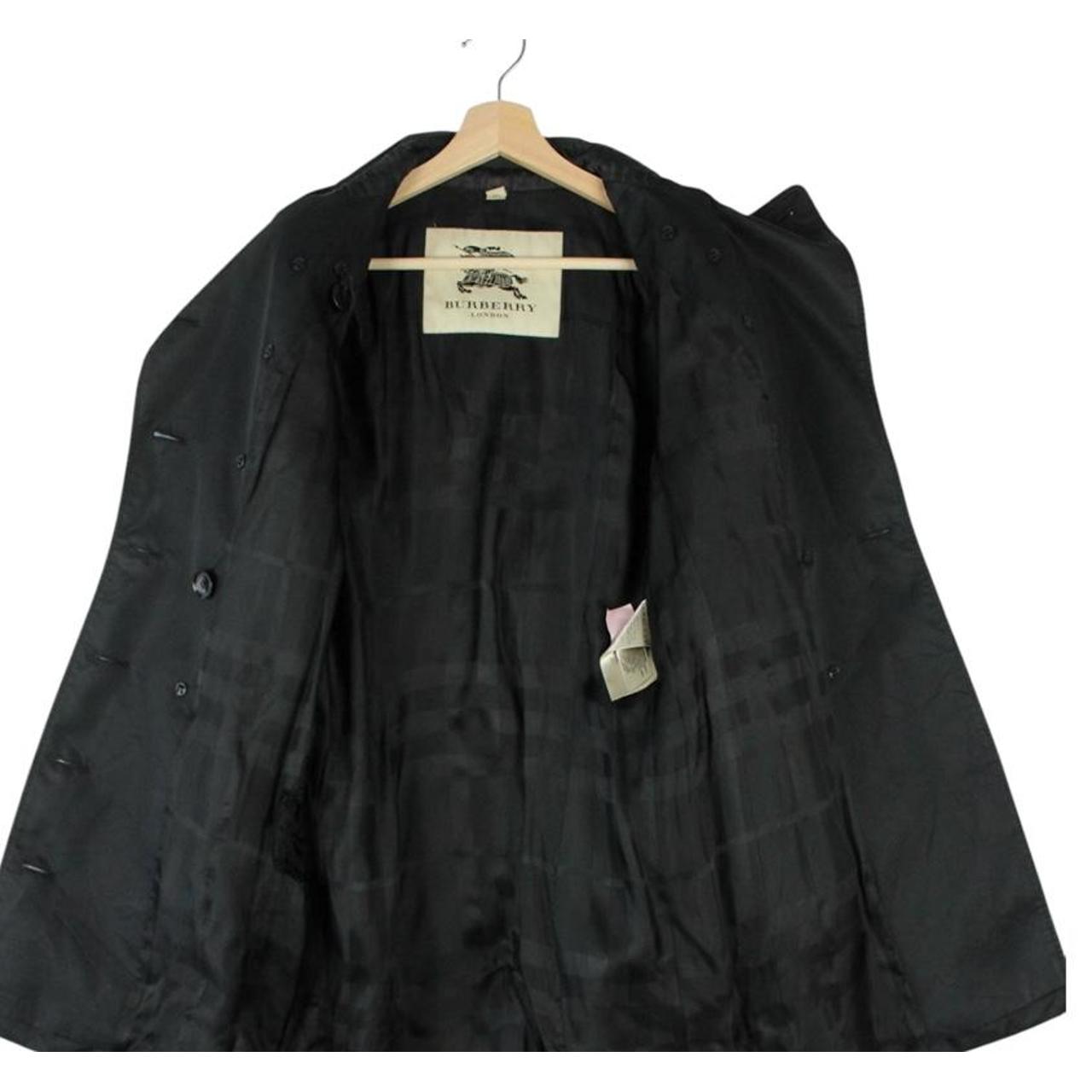 Burberry black double breasted belted trench coat with logo detailing and classic design.