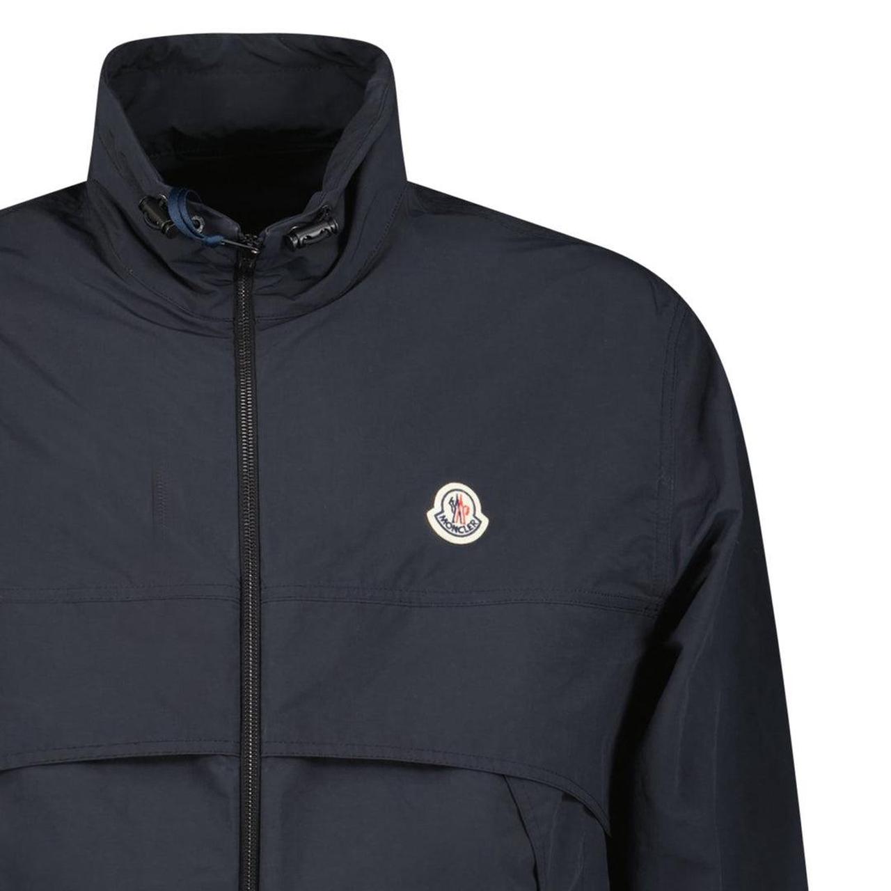 Moncler black windbreaker jacket with full zip, logo patch on sleeve, lightweight material.