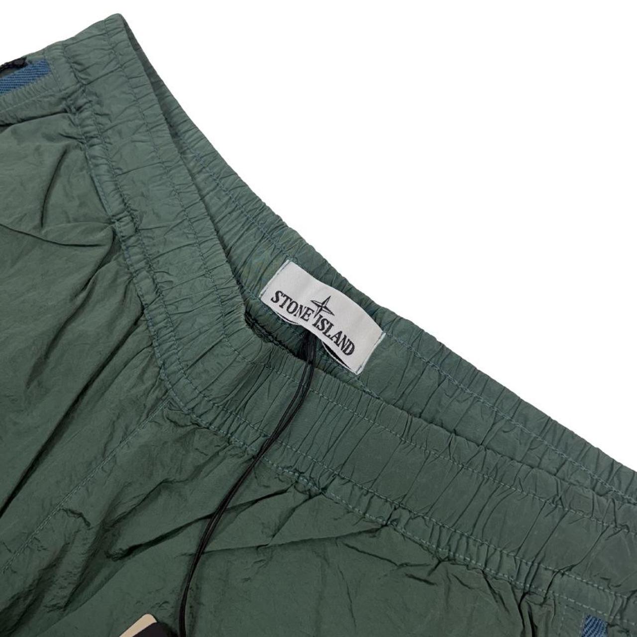 Stone Island green nylon metal trousers with logo patch and sleek finish.