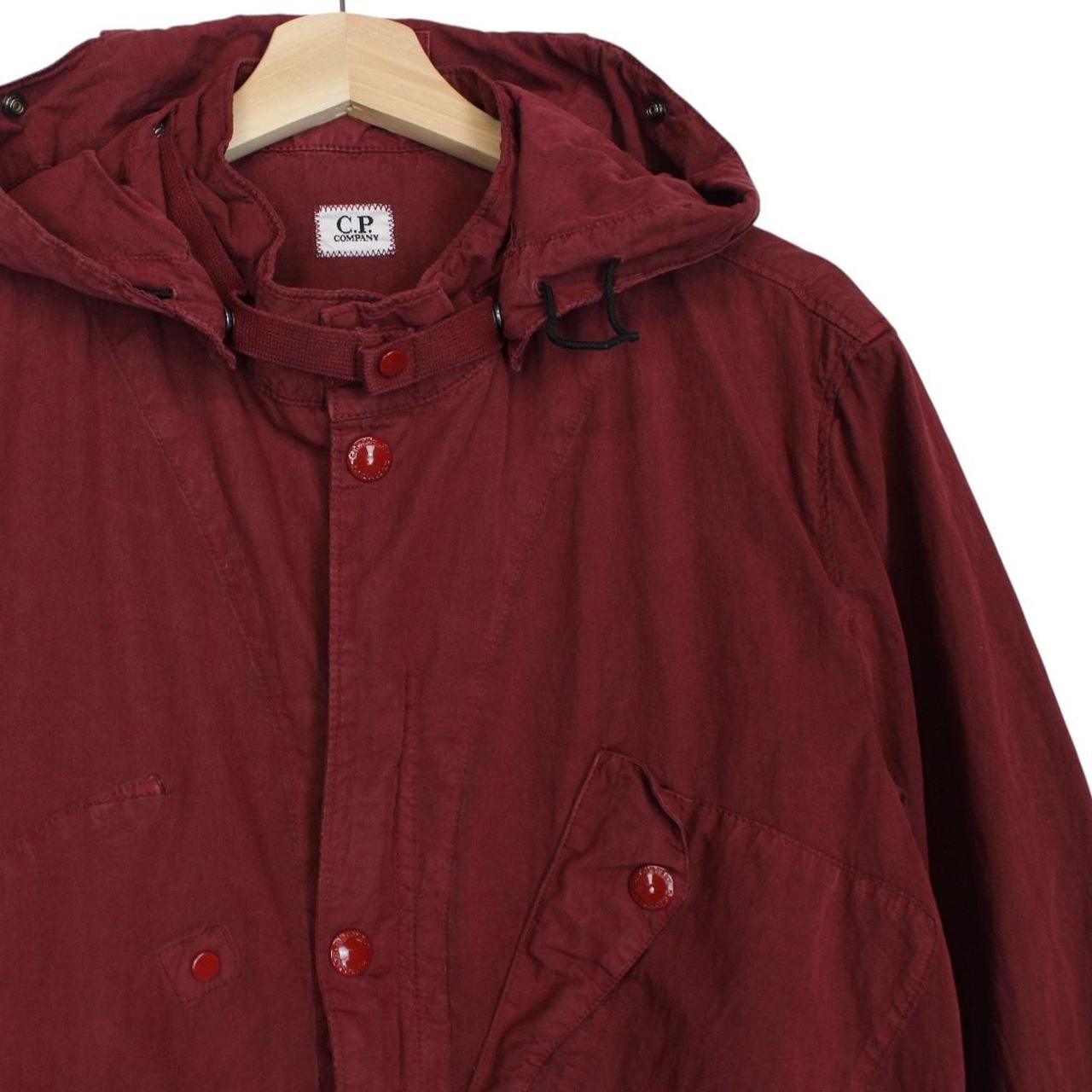CP Company burgundy jacket with goggle detail and full zip closure.