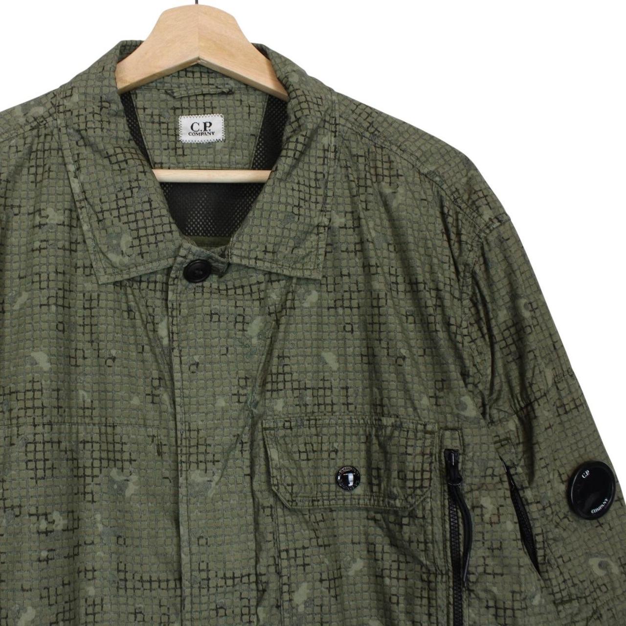 CP Company khaki green overshirt jacket with digital camouflage pattern and lens detail.