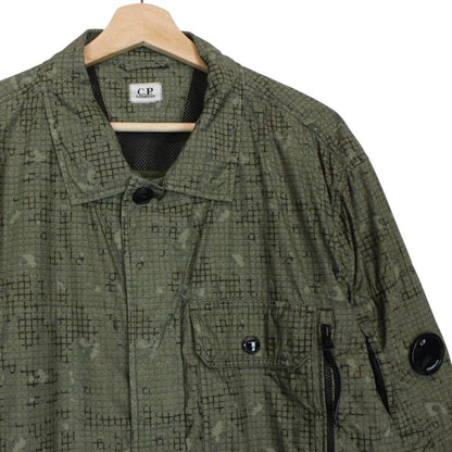 CP Company khaki green overshirt jacket with digital camouflage pattern and lens detail.
