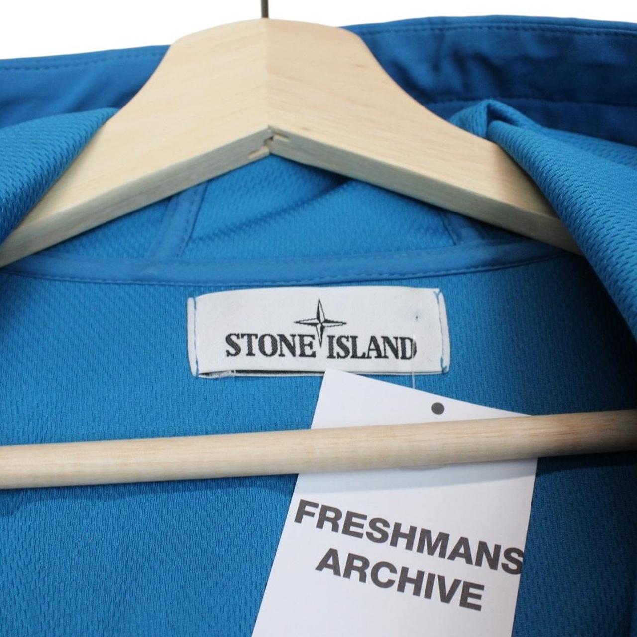 Stone Island blue full zip jacket with logo patch and soft shell material.