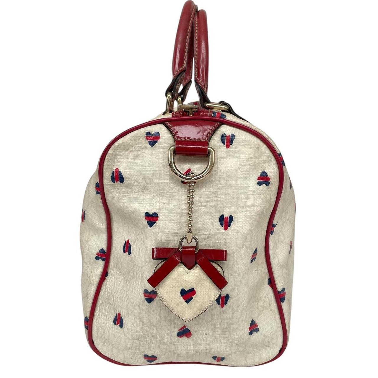 Gucci cream duffel bag with red monogram heart print and logo detailing.