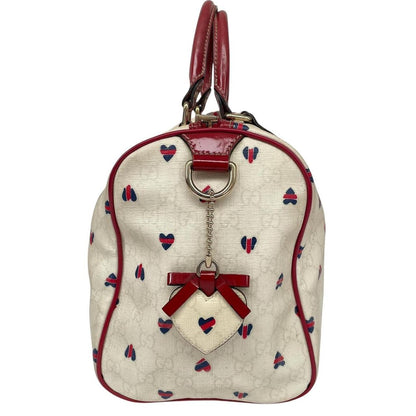 Gucci cream duffel bag with red monogram heart print and logo detailing.