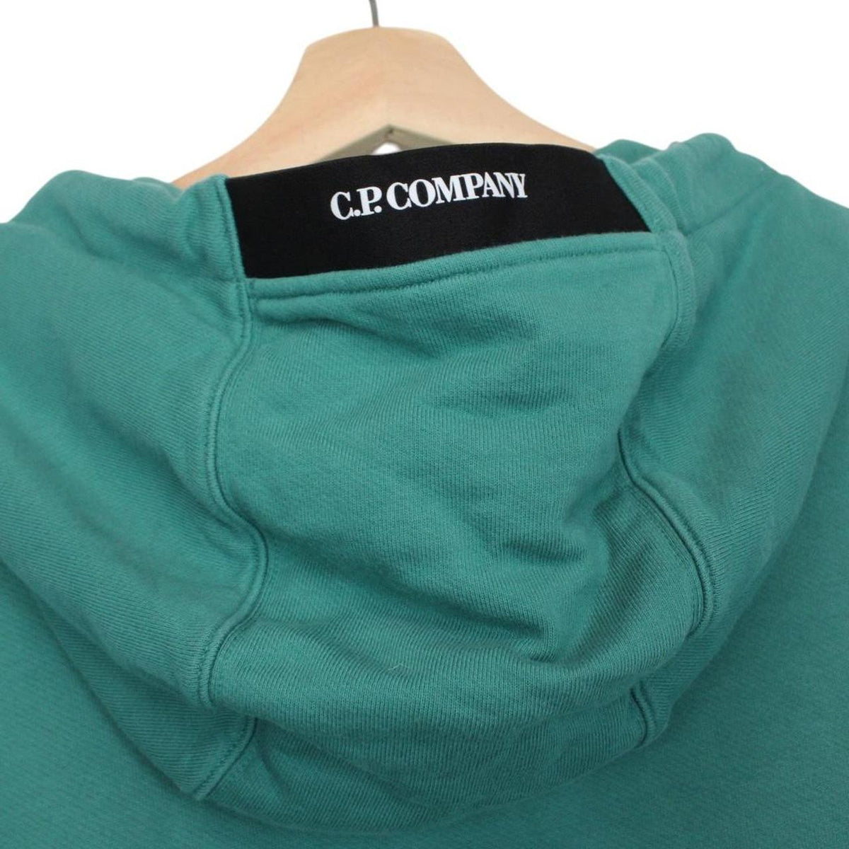 CP Company green hoodie jumper with lens detail and cotton material.