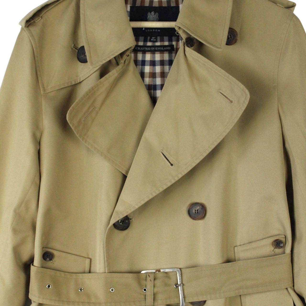 Aquascutum tan brown double breasted trench coat with house check pattern and belted waist.