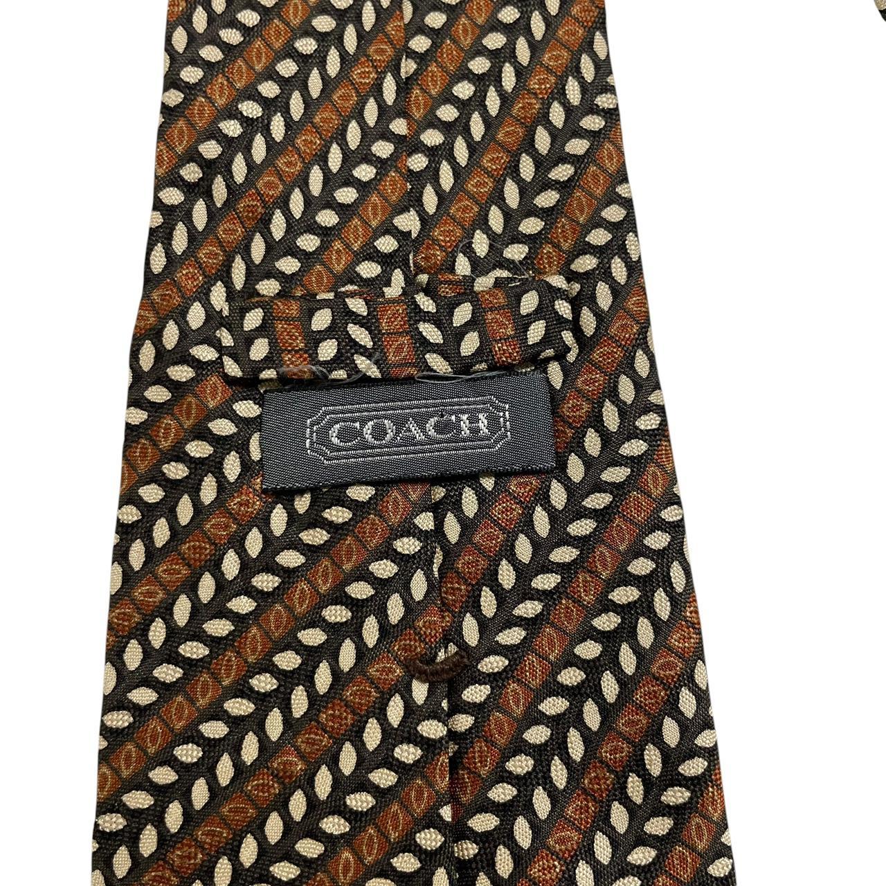 Coach brown floral print silk tie with intricate flower patterns and smooth texture.