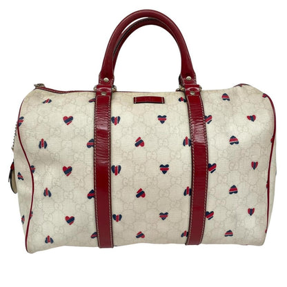 Gucci cream duffel bag with red monogram heart print and logo detailing.