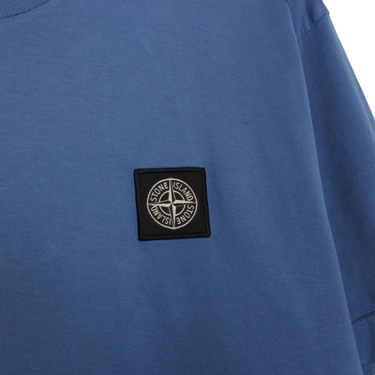 Stone Island blue short sleeve cotton t-shirt with compass logo and visible wear marks.