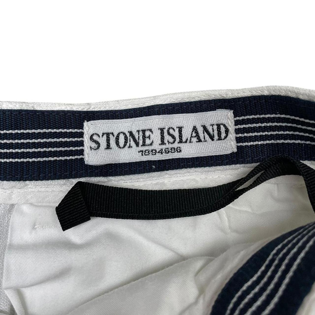 Stone Island white linen Bermuda shorts with logo patch and subtle stains.