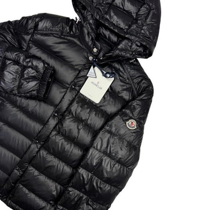 Moncler black hooded puffer jacket with logo patch and nylon material.
