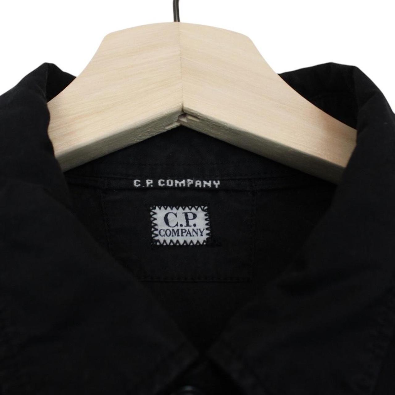 CP Company black button-up jacket with lens detail and cotton material.