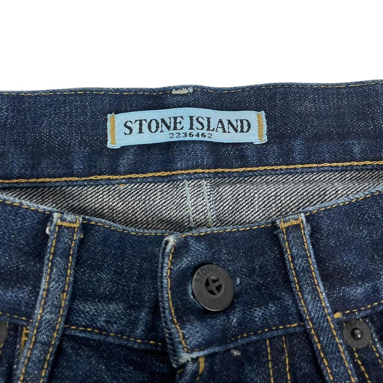 Stone Island navy blue straight jeans with logo patch and visible scuff on left knee.