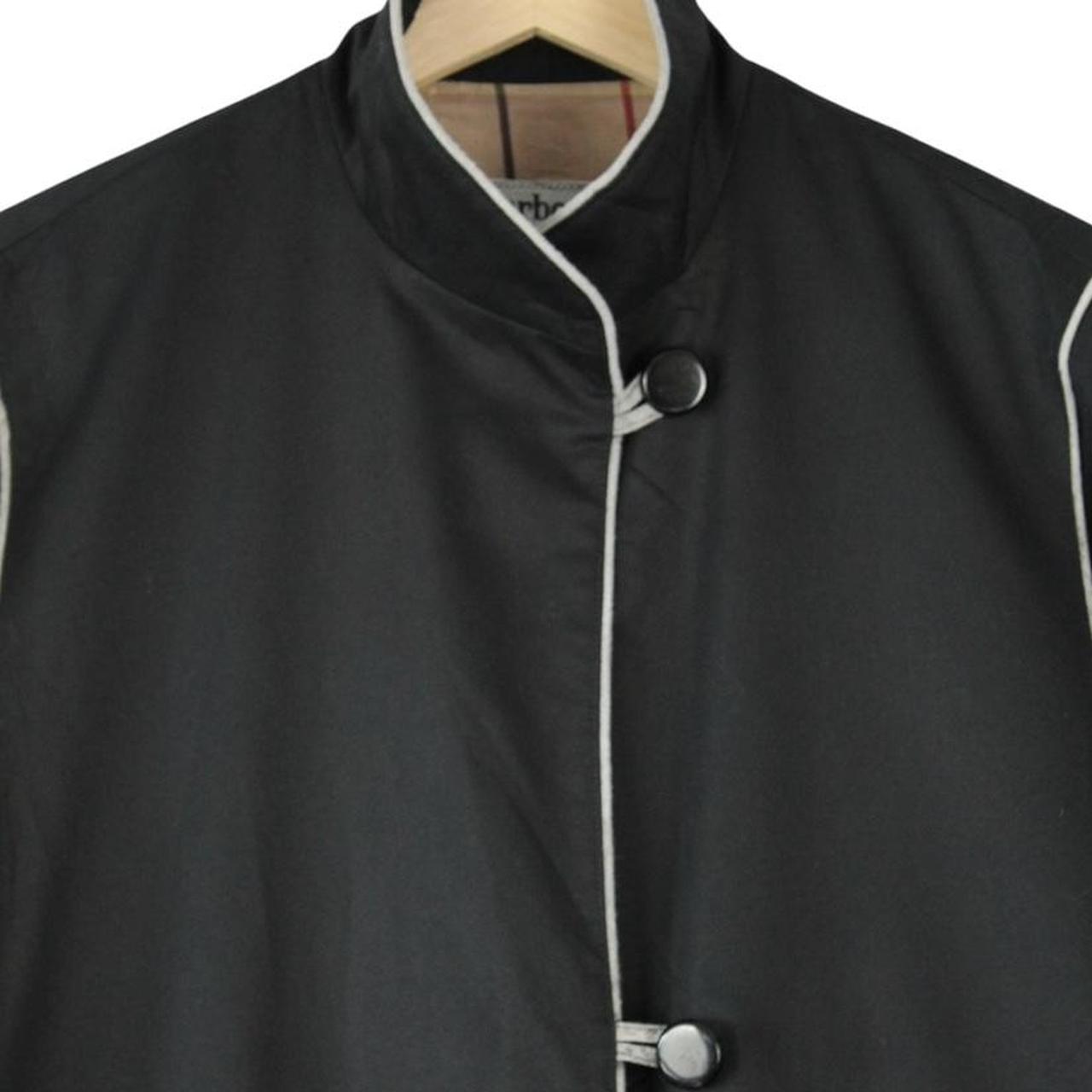 Burberry black cotton trench coat with single breasted design and classic logo detailing.