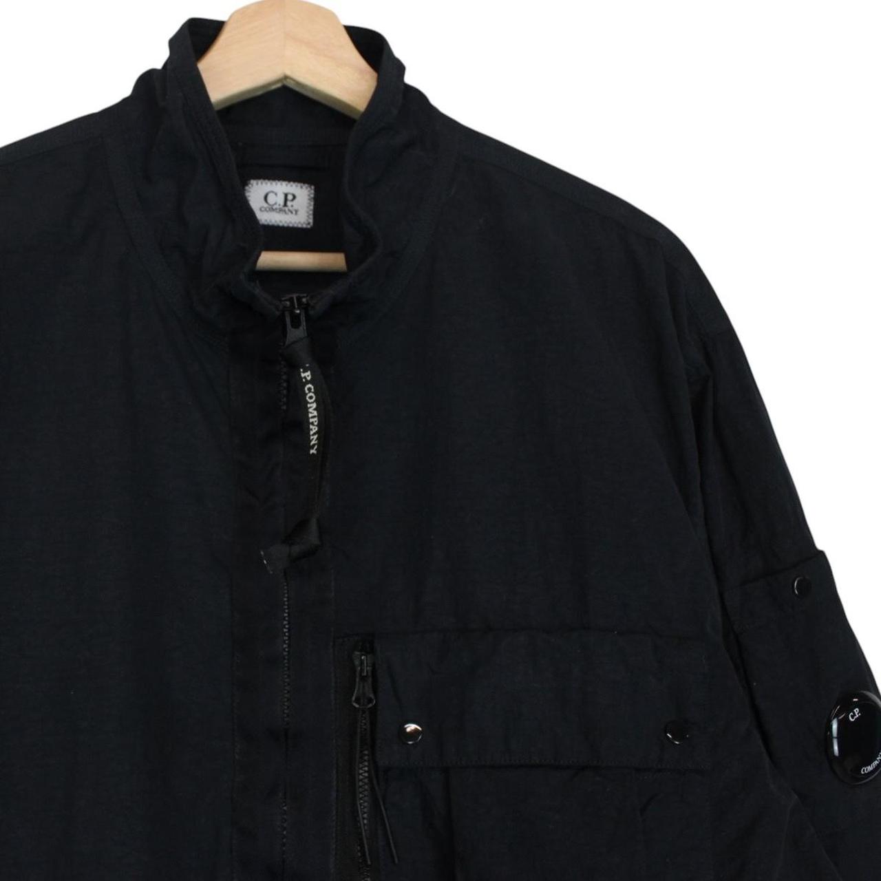 CP Company navy blue jacket 1/4 zip with lens detail and flat nylon material.