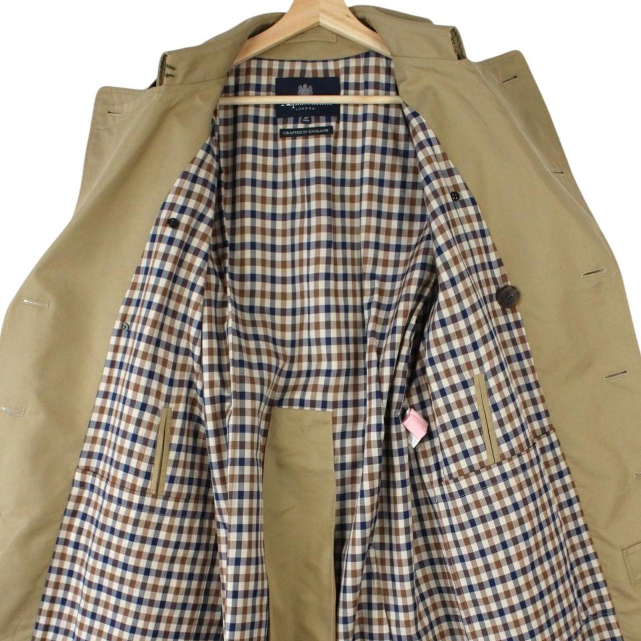 Aquascutum tan brown double breasted trench coat with house check pattern and belted waist.