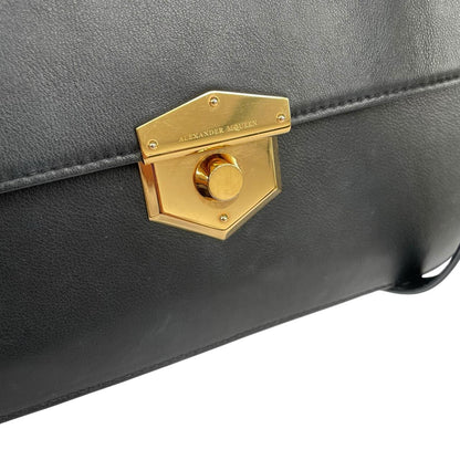 Alexander McQueen black and gold leather messenger bag with logo detailing and faint scratches.