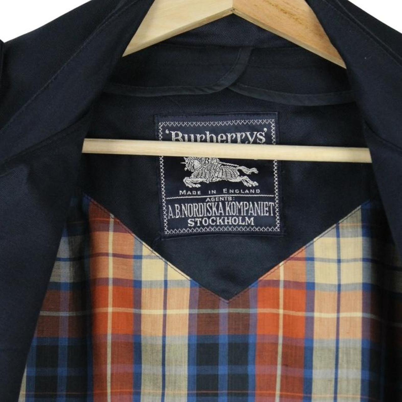 Burberry navy blue double breasted trench coat with belted waist and classic check lining.