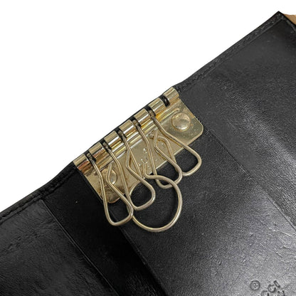 Gucci black leather key case featuring GG monogram pattern and scuffed details.