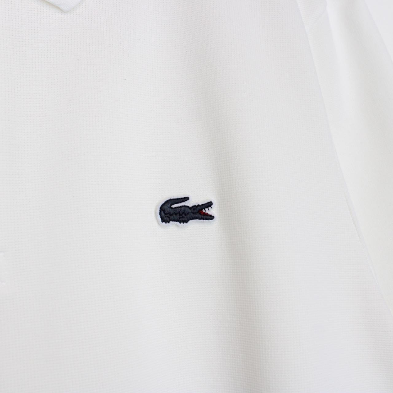 Lacoste white short sleeve polo shirt with green crocodile logo and cotton material.