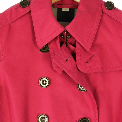 Burberry pink double breasted belted trench coat with classic check lining and logo buttons.