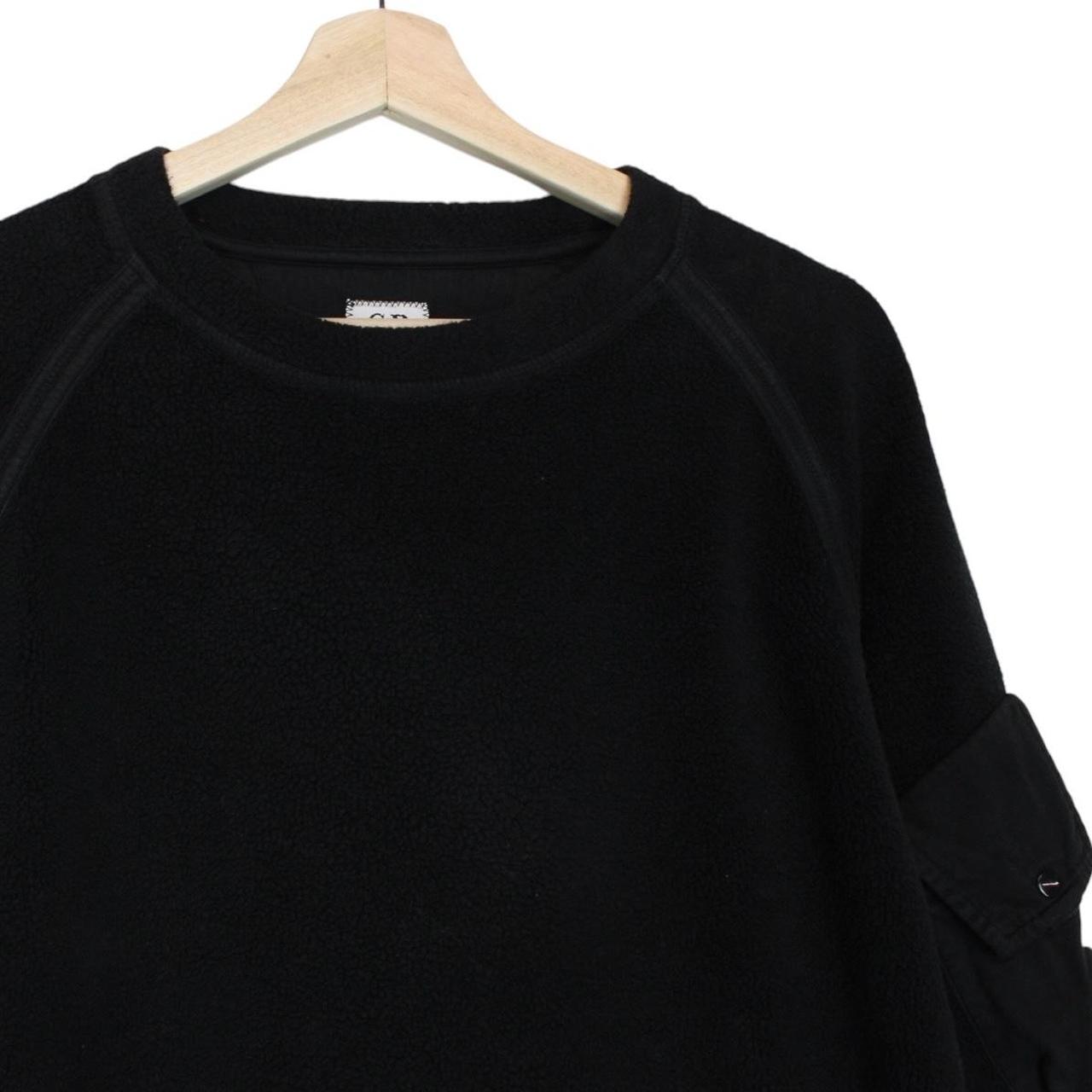 CP Company black fleece jumper with raglan sleeves and iconic lens detail.