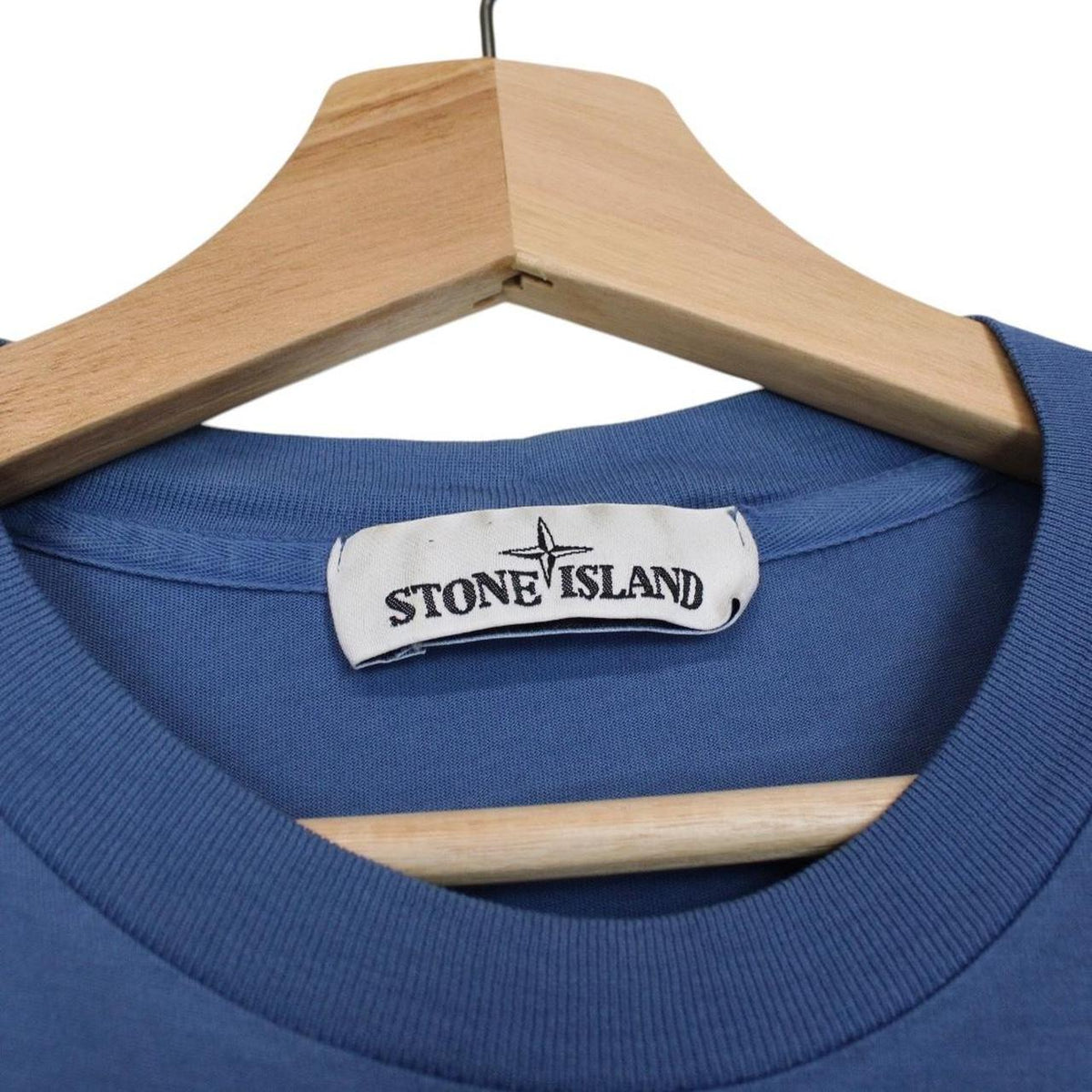 Stone Island blue short sleeve cotton t-shirt with compass logo and visible wear marks.