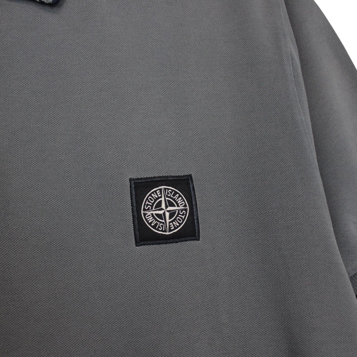 Stone Island grey polo shirt with embroidered compass logo and cotton material.