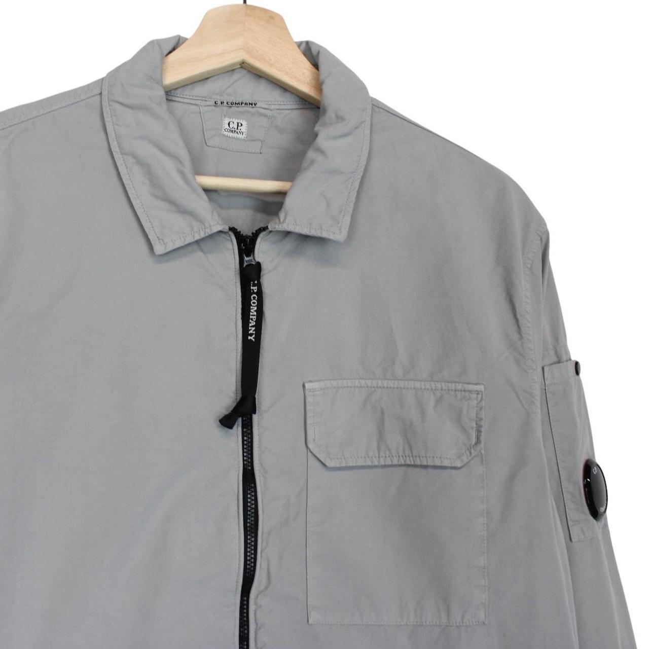 CP Company grey full zip overshirt jacket with lens detail and cotton material.