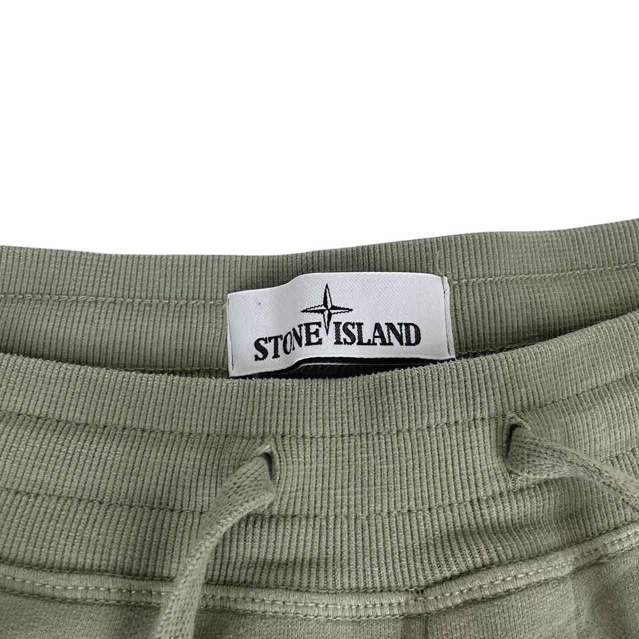 Stone Island green joggers with logo patch and cotton material, visible wear marks.