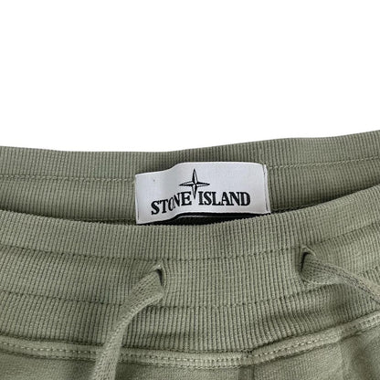 Stone Island green joggers with logo patch and cotton material, visible wear marks.