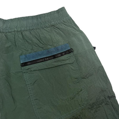 Stone Island green nylon metal trousers with logo patch and sleek finish.
