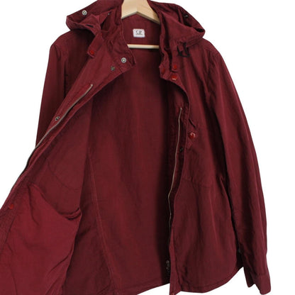 CP Company burgundy jacket with goggle detail and full zip closure.