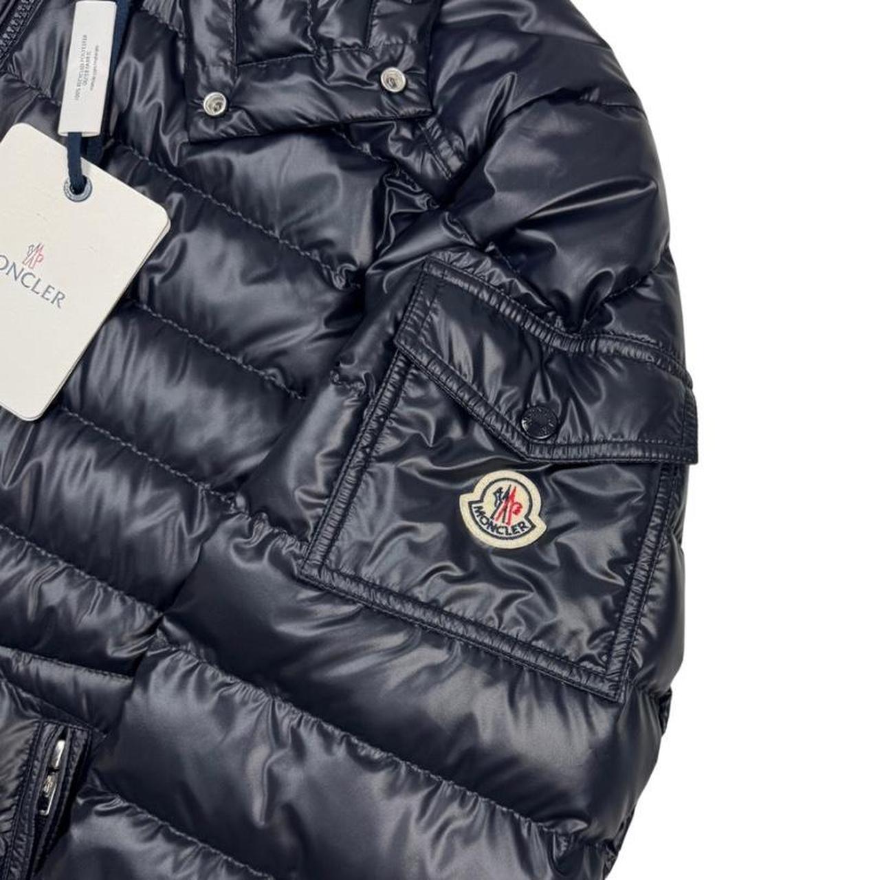 Moncler navy blue hooded puffer jacket with logo patch and nylon material.