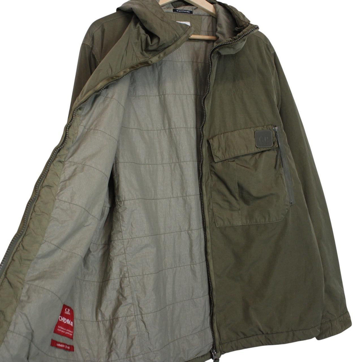 CP Company green hooded jacket with chrome detailing and logo patch on sleeve.