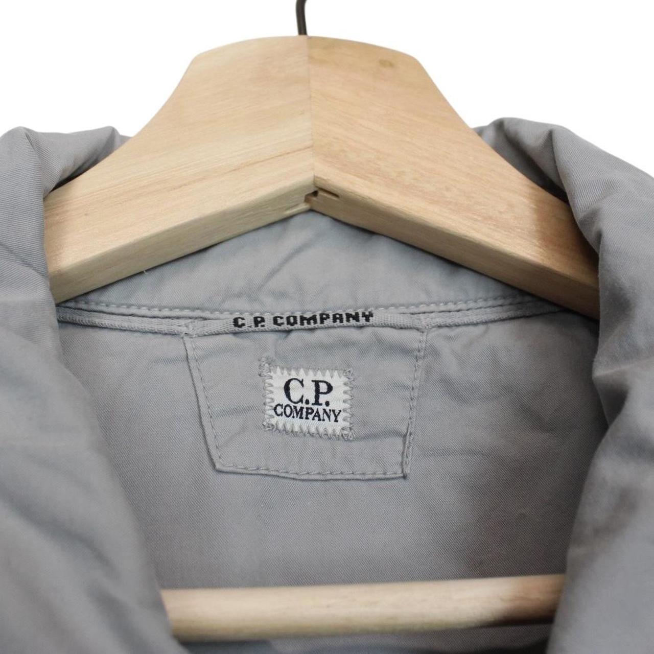 CP Company grey full zip overshirt jacket with lens detail and cotton material.