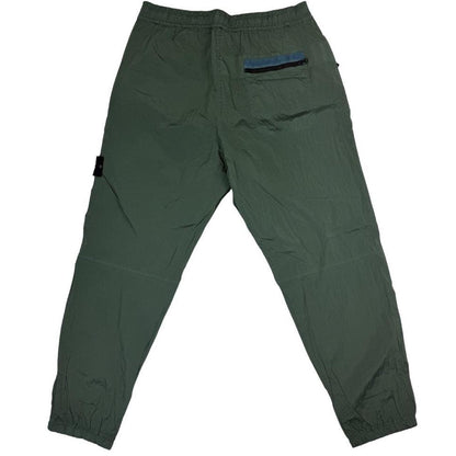 Stone Island green nylon metal trousers with logo patch and sleek finish.
