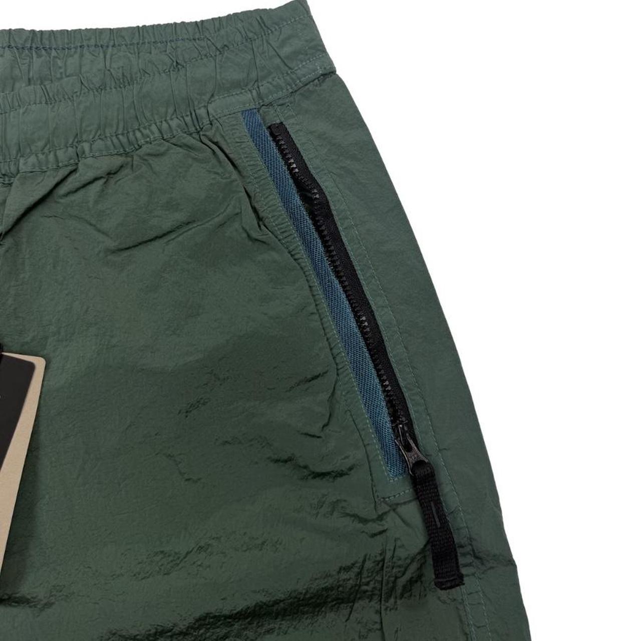 Stone Island green nylon metal trousers with logo patch and sleek finish.