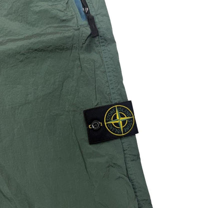 Stone Island green nylon metal trousers with logo patch and sleek finish.