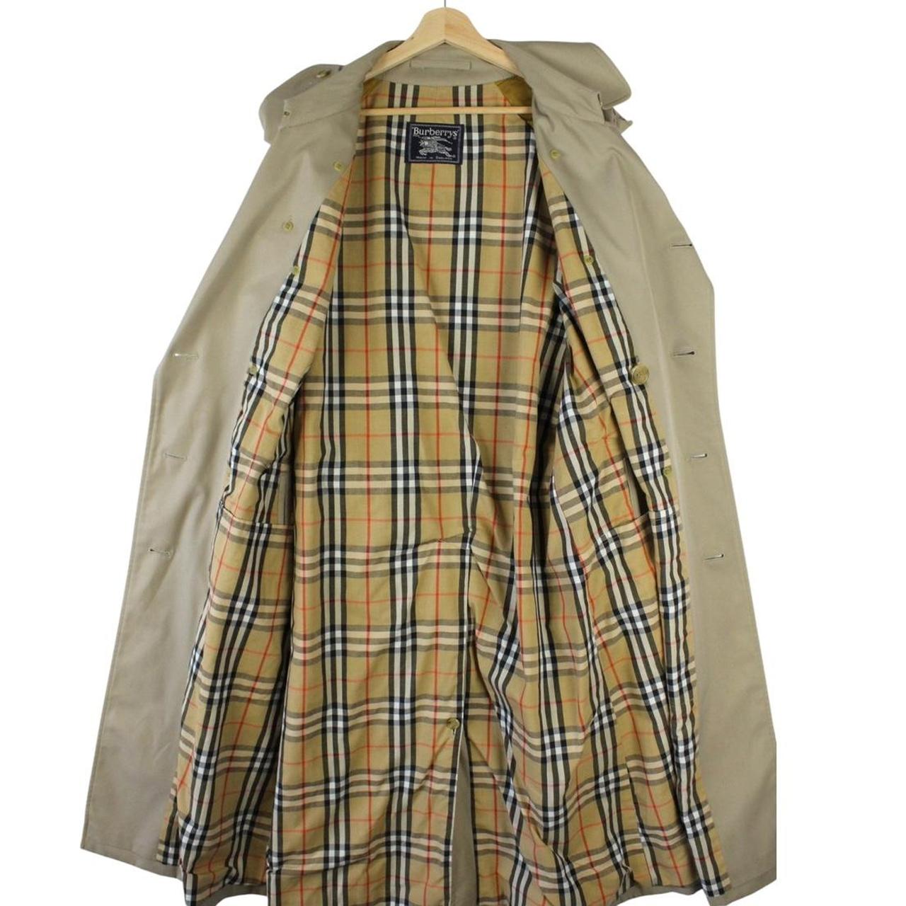 Burberry beige double-breasted belted trench coat with classic check lining and logo detail.