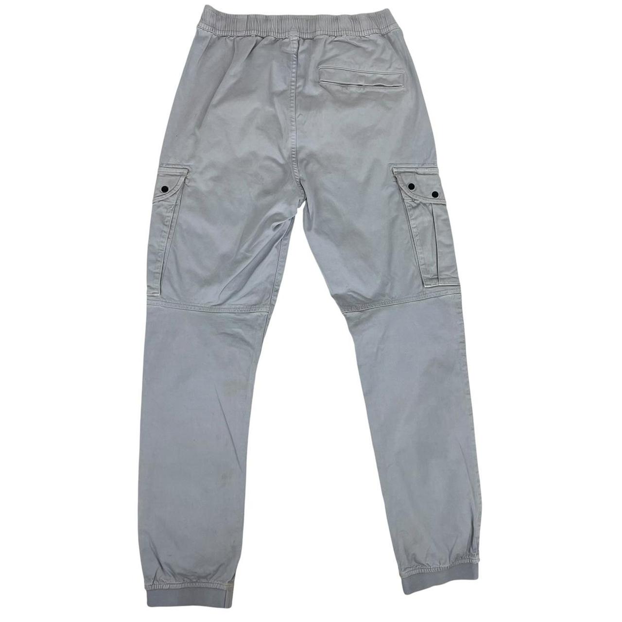 Stone Island blue cargo trousers with logo patch and RE-T fit, visible stain on left leg.