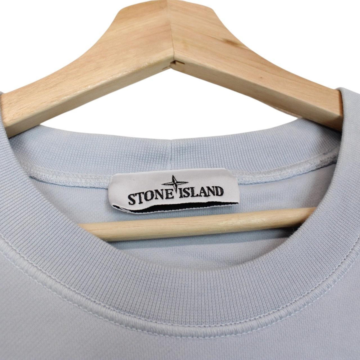 Stone Island blue cotton sweatshirt with logo patch and faded left sleeve.