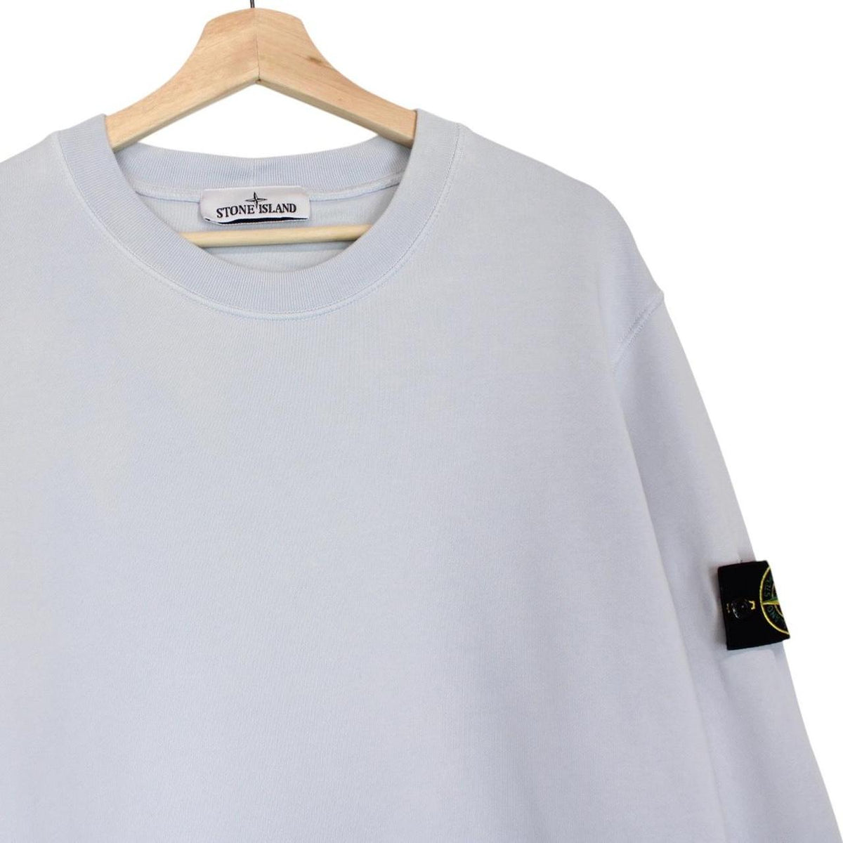 Stone Island blue cotton sweatshirt with logo patch and faded left sleeve.