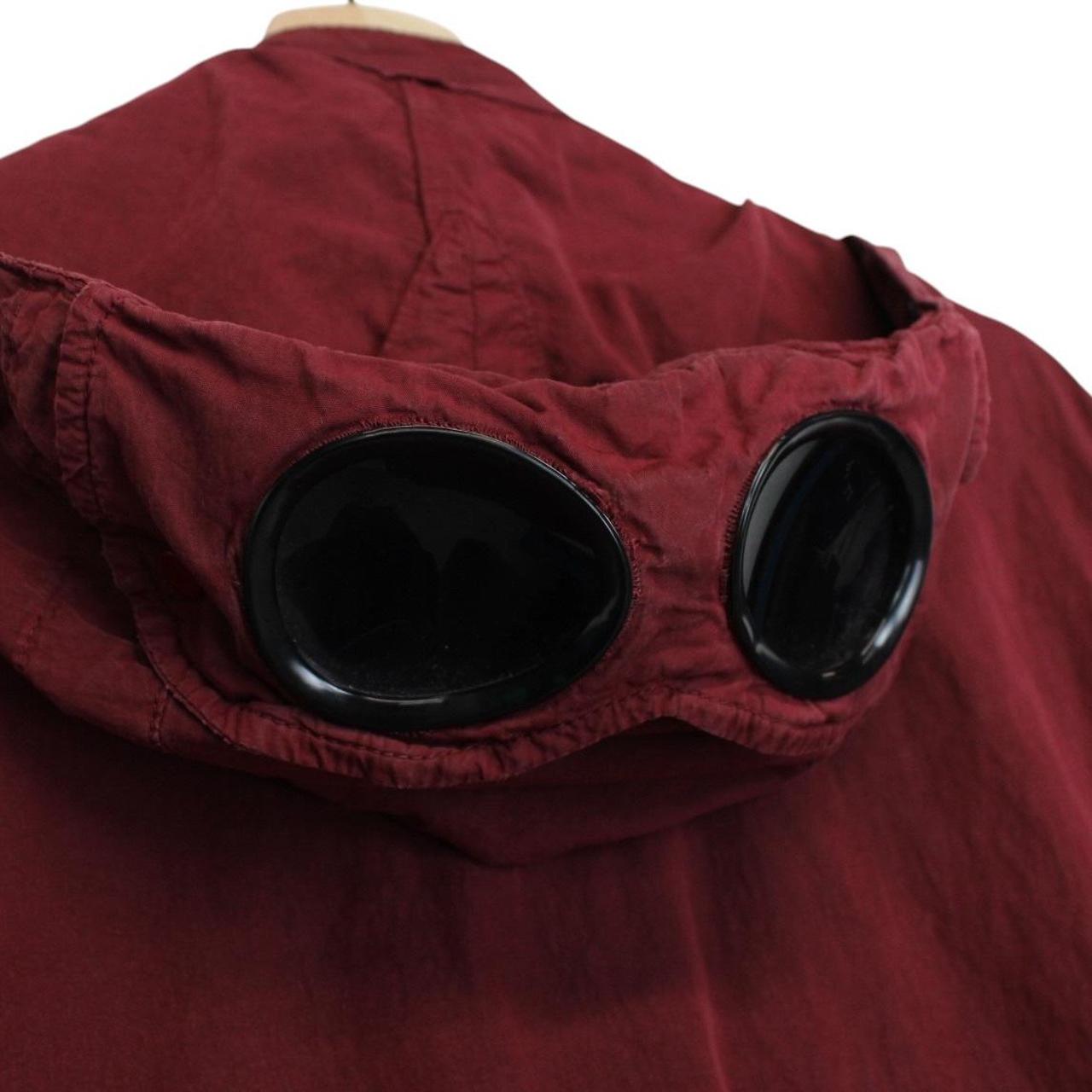 CP Company burgundy jacket with goggle detail and full zip closure.