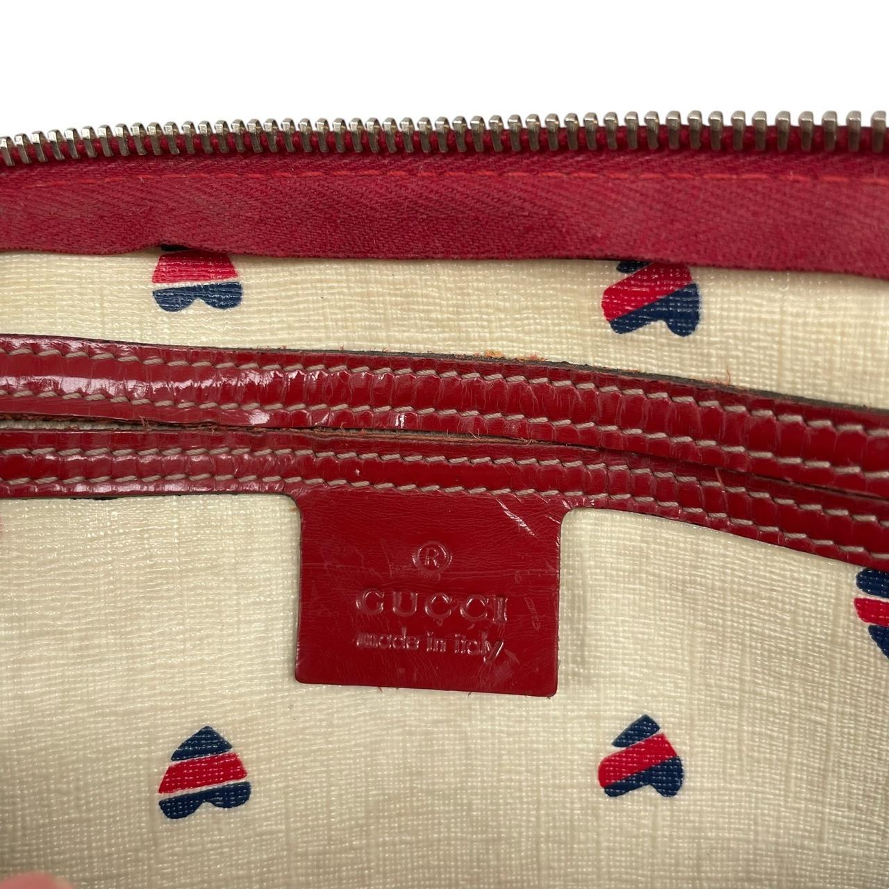 Gucci cream duffel bag with red monogram heart print and logo detailing.