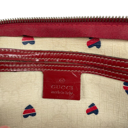 Gucci cream duffel bag with red monogram heart print and logo detailing.