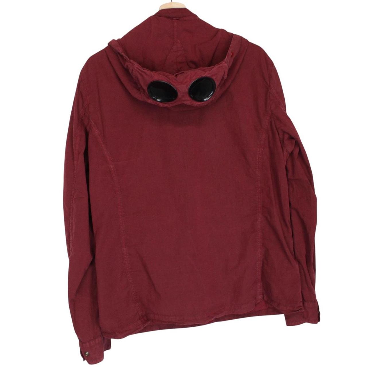 CP Company burgundy jacket with goggle detail and full zip closure.